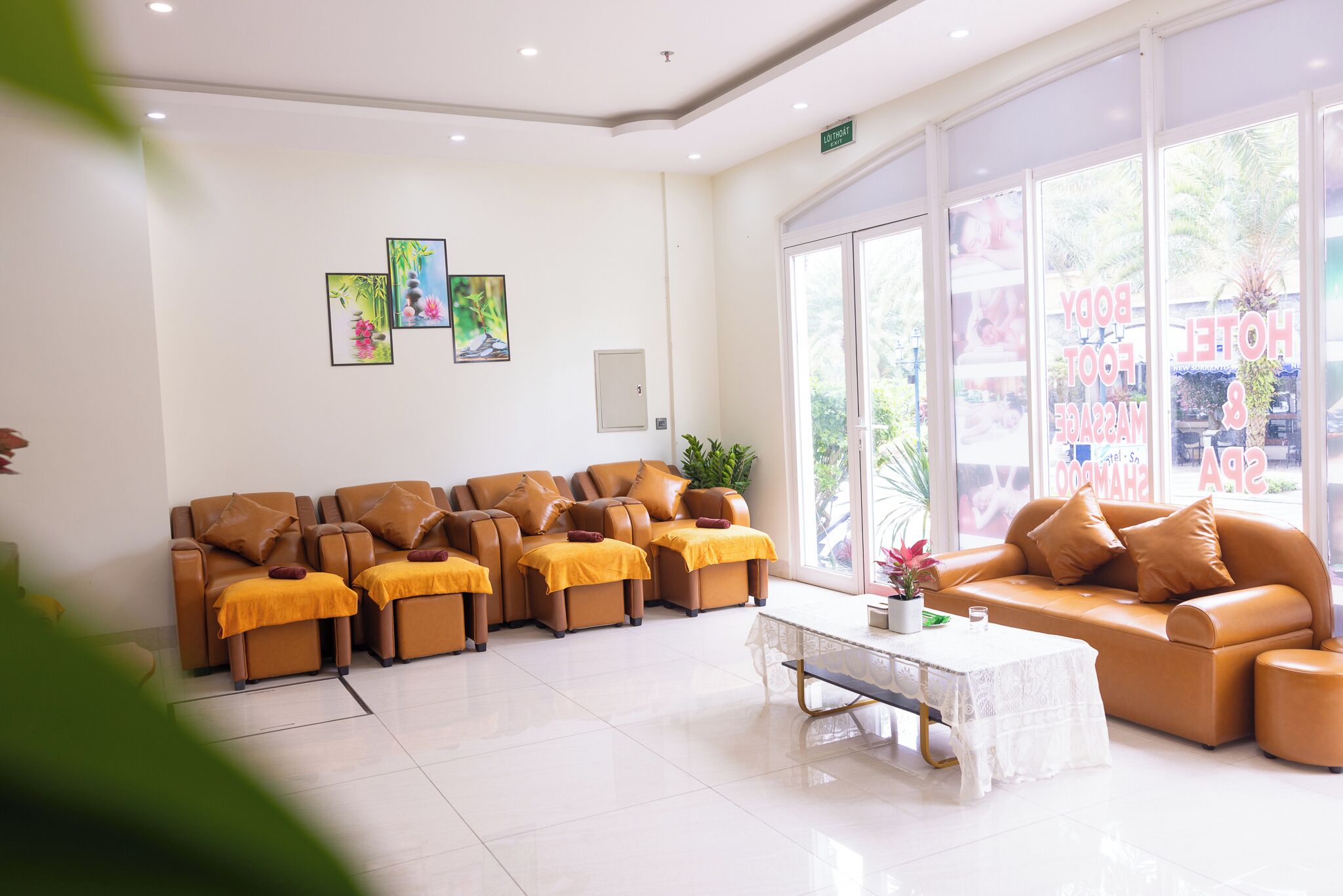 Un hall de hotel con varios sofás de cuero, una mesa de centro blanca y grandes ventanales con vistas al exterior.