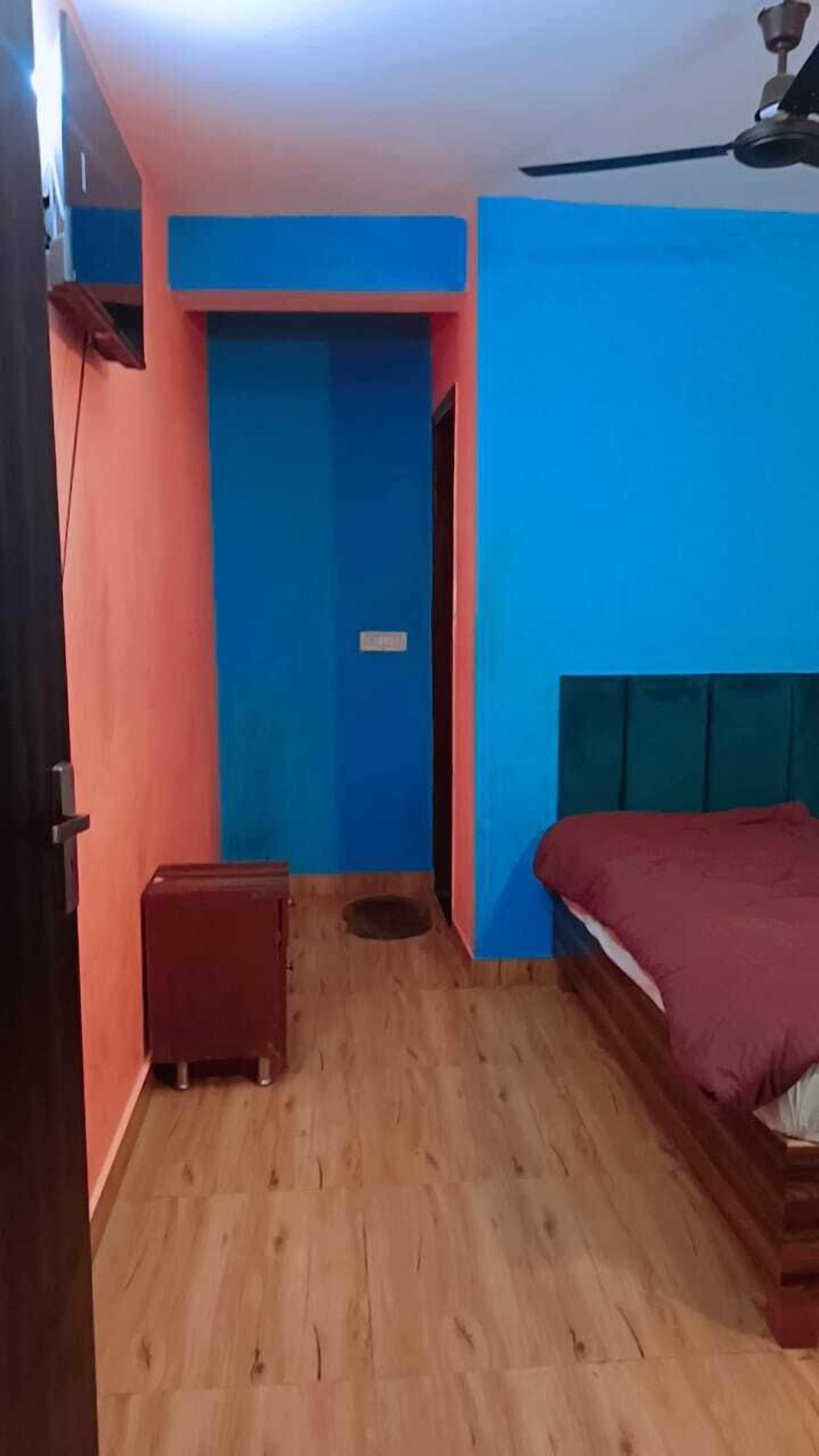 Une pièce avec un lit, un petit tabouret et un ventilateur de plafond.