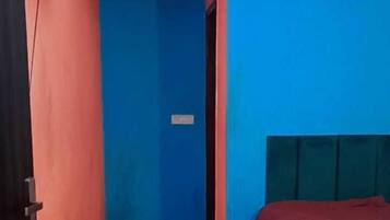 Une pièce avec un lit, un petit tabouret et un ventilateur de plafond.