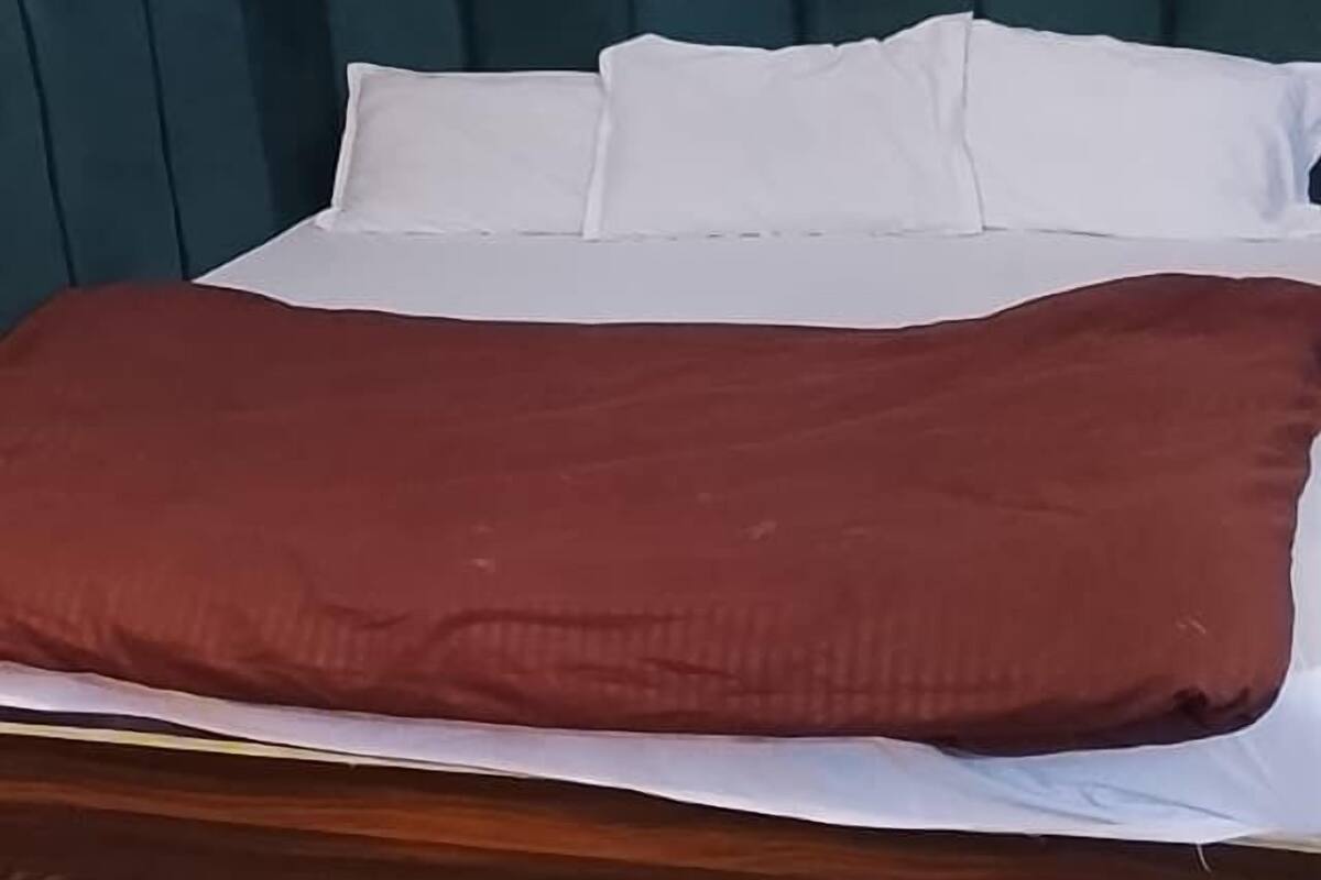 A bed with a dark headboard, white pillows, and a brown blanket.