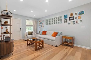 Una sala de estar con un sofá blanco, una mesa de centro de madera y una estantería.