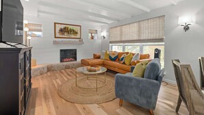 Ein modernes Wohnzimmer mit Kamin, einer großen Couch, einem Couchtisch und einem Fernseher.