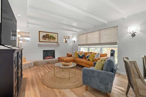Una sala de estar moderna con chimenea, un sofá grande, una mesa de centro y una televisión.