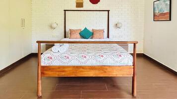 A bedroom with a wooden bed, white brick wall, and a painting on the wall.