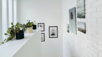 A modern interior with a white brick wall, framed artwork, and potted plants on a white ledge.