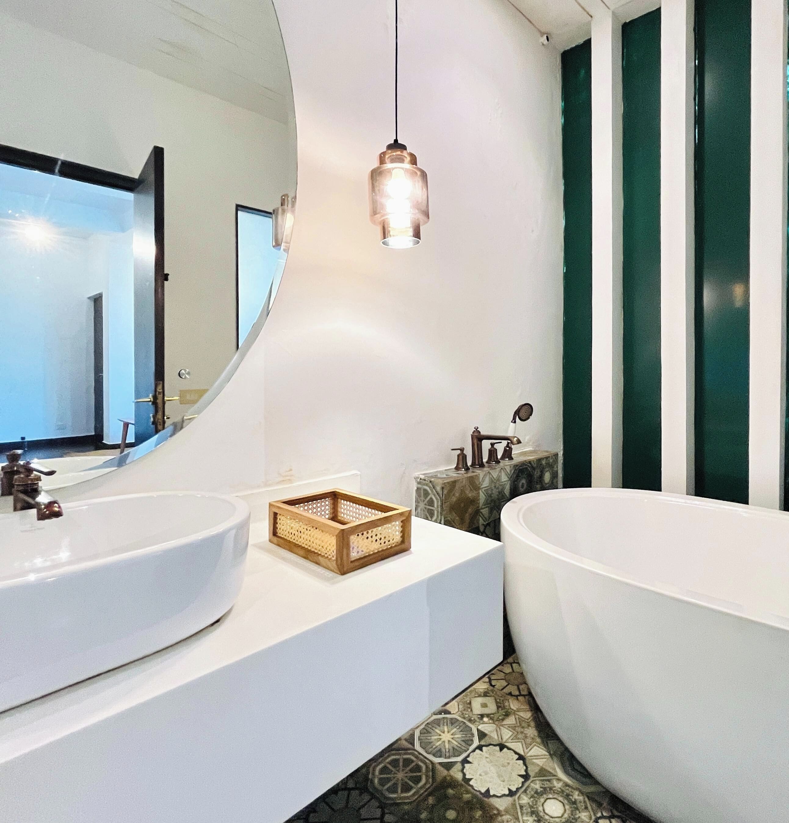 A modern bathroom with two sinks, a large bathtub, and a hanging light fixture.