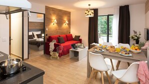 Camera d'albergo moderna con zona pranzo, un divano rosso e preparazione per la colazione.