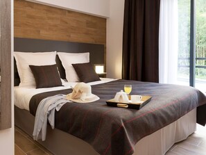 A hotel room with a large bed, a wooden headboard, and a window with curtains. - Résidence Odalys Collection Isatis by Interhome (Chamonix)
