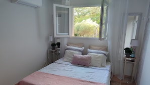 Ein ordentlich eingerichtetes Schlafzimmer mit Bett, Nachttischen, einem Fenster und einem Spiegel.