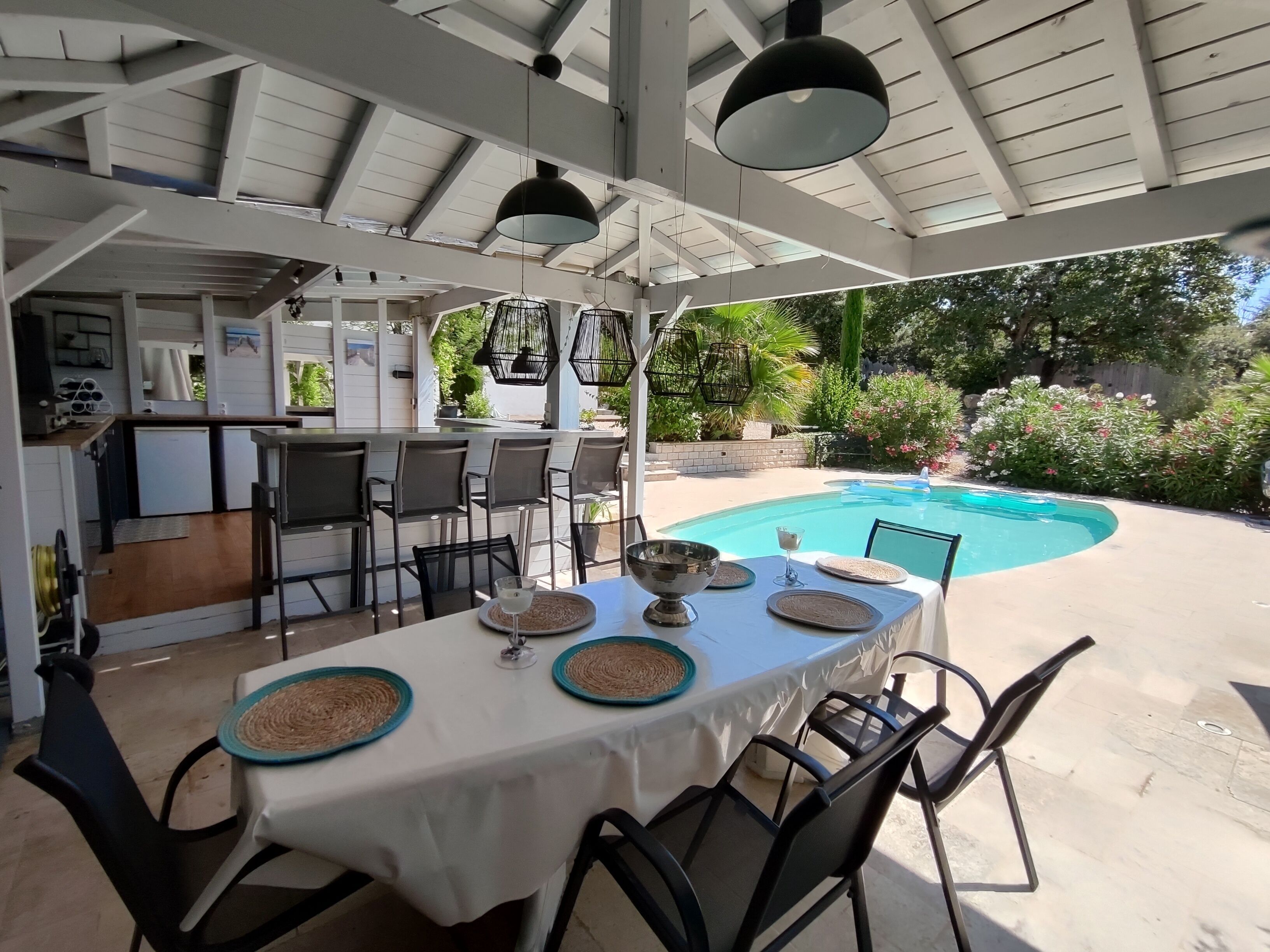 An outdoor dining area with a pool in the background.