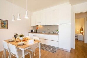 A modern kitchen with white cabinets, a dining table with chairs, and a small island with a sink. - Sea Breeze Suite – Your Haven of Light and Comfort (Bari)