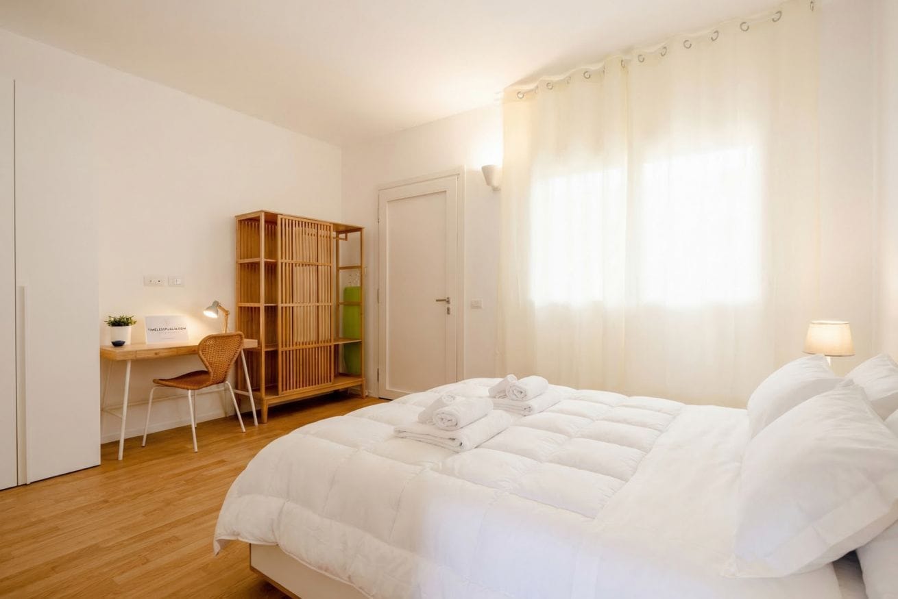 Una camera da letto con un letto, una scrivania, una sedia, un armadio e una finestra con tende.