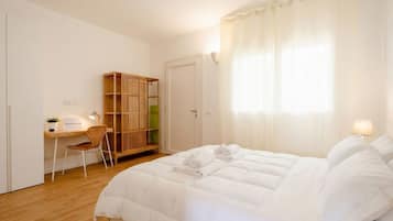 Una camera da letto con un letto, una scrivania, una sedia, un armadio e una finestra con tende.