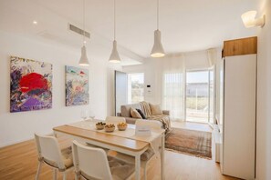 A modern living room with a dining area, a sofa, and artwork on the walls. - Sea Breeze Suite – Your Haven of Light and Comfort (Bari)
