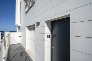 A modern building with a closed door, a balcony with a railing, and a clear sky in the background. - Sea Breeze Suite – Your Haven of Light and Comfort (Bari)