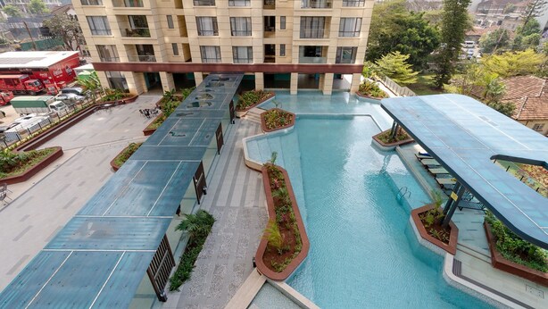 A hotel with a rooftop pool, multiple balconies, and a parking area with delivery trucks. - Alba Gardens B1102 (Nairobi)