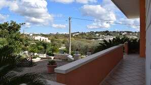 A balcony with a view of a town, potted plants, and a clear sky. - Valley vacation home (Locorotondo)