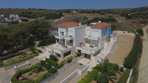 A modern two-story residential building with a flat roof, a balcony, and a small garden area. - Entire home in Lilikas, Greece (Kalamoti)