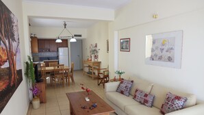 A living room with a sofa, coffee table, and dining area with chairs and a table. - Entire home in Lilikas, Greece (Kalamoti)