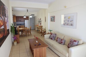 A living room with a sofa, coffee table, and dining area with chairs and a table. - Entire home in Lilikas, Greece (Kalamoti)