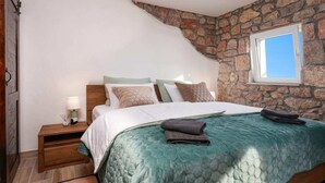 Una camera da letto con parete in pietra, struttura del letto in legno e una finestra.