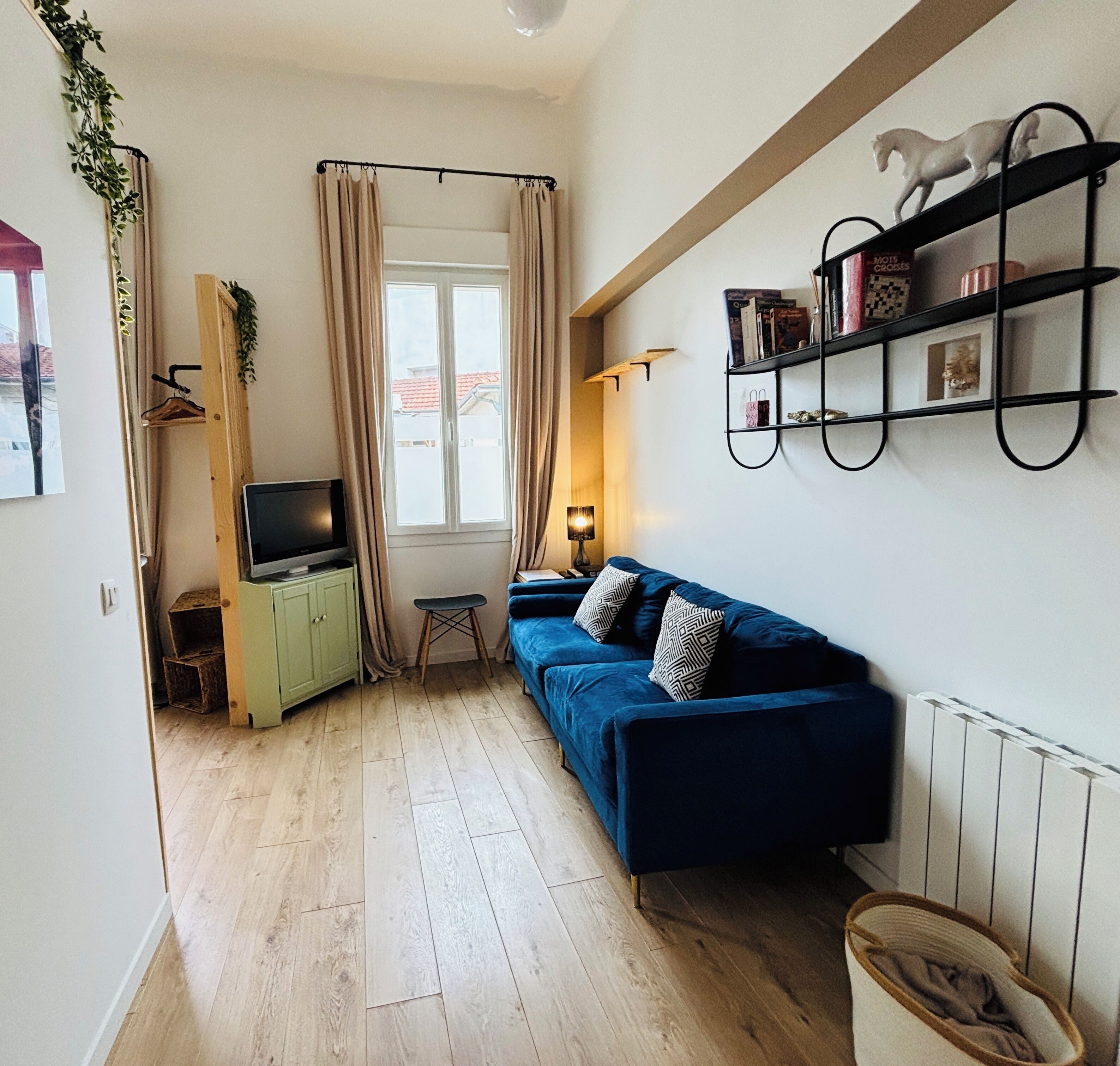 A compact living space with a sofa, a television, a small table, and a bookshelf.