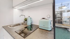 A modern kitchen with a stainless steel sink, a kettle, and a toaster. - The Homeboat Company - PDN (Lisboa)