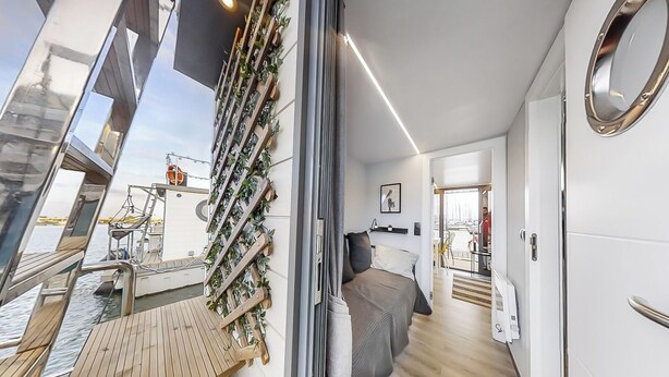 A modern interior with a bed, wooden deck, and a view of the water. - The Homeboat Company - PDN (Lisboa)