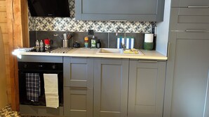 Een moderne keuken met grijze kastjes, een betegelde spatwand en een inbouwoven.