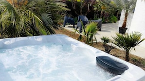 Ein Whirlpool mit Blick auf einen Garten und Sitzgelegenheiten im Freien.