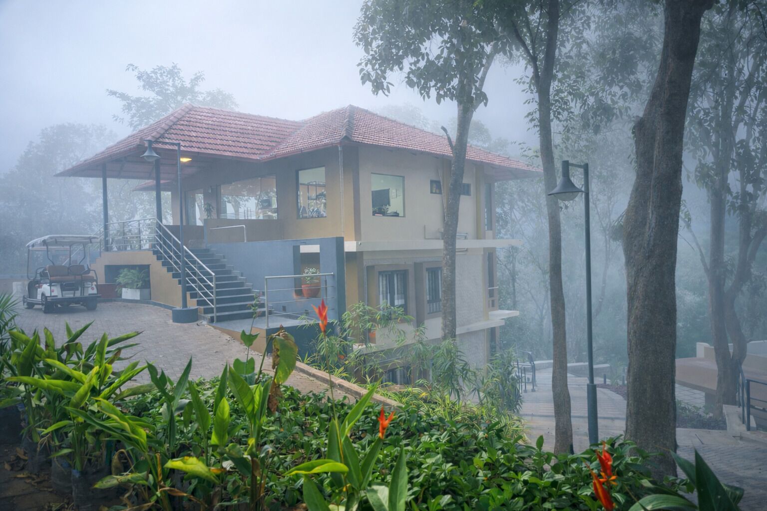 A two-story building with a red-tiled roof, a staircase, and a golf cart parked in front.
