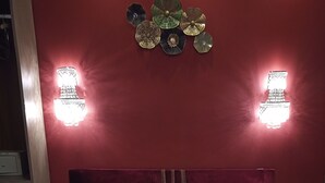 En pænt redt seng med hvide sengetøj og håndklæder, en rød væg og to vægmonterede lamper.