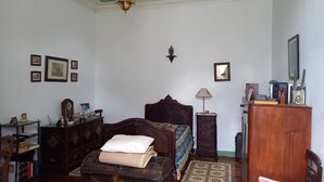A traditional room with a wooden bed, a small table, a dresser, and a mirror on the wall. - Charming farmhouse for rent (Riachos)