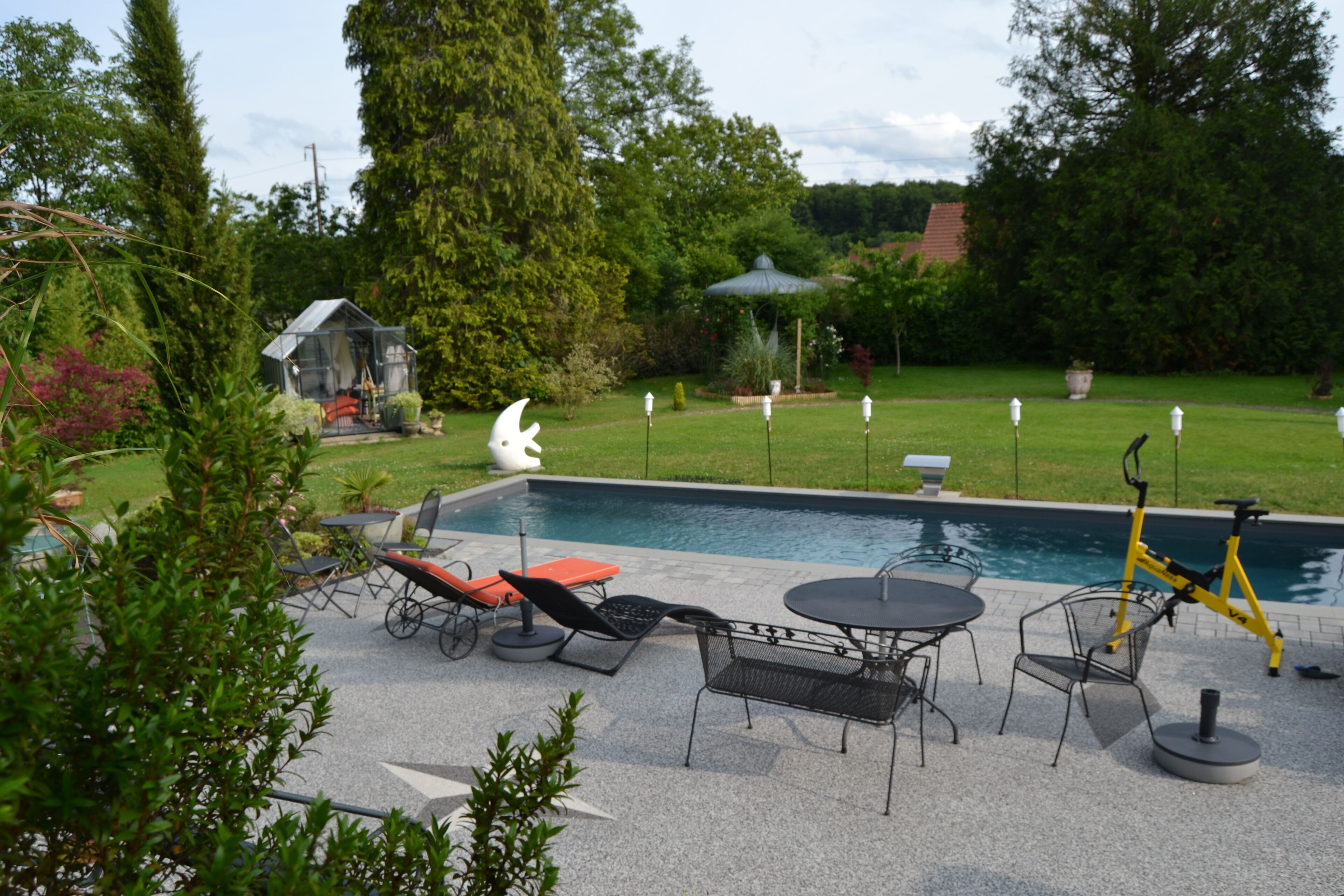 A backyard with a swimming pool, outdoor furniture, a gazebo, and a birdhouse.