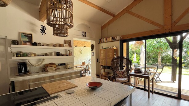 A kitchen with a large island, wooden beams, and a dining area with a view of the outdoors. - Wooden house, côte landaise 5min ocean, lakes, ideal family, animals accepted! (Biscarrosse)