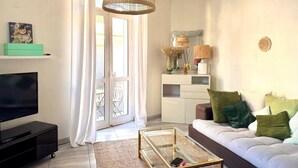 A living room with a sofa, TV, and a glass coffee table. - Duplex with terrace and balcony Cannes center (Croisette & Palais des festivals) (Cannes)