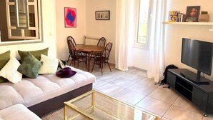 A living room with a sofa, coffee table, TV, dining table, chairs, and a hanging light fixture. - Duplex with terrace and balcony Cannes center (Croisette & Palais des festivals) (Cannes)