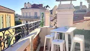 A rooftop terrace with white bar stools, a white table, and a decorative balustrade. - Duplex with terrace and balcony Cannes center (Croisette & Palais des festivals) (Cannes)
