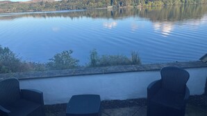 A lakeside patio with two wicker chairs and a small table, overlooking a calm lake and forested hills. - Portsonachan Hotel (Dalmally)