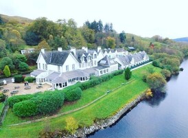 A large, white, multi-story building with a symmetrical roofline, located beside a calm river.