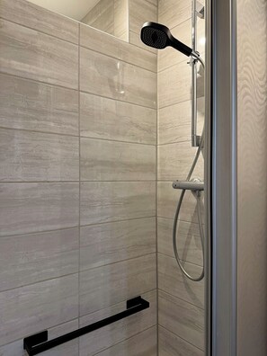 A shower with a handheld showerhead, a handheld showerhead, and a glass door. - Helene vacation apartment with balcony and Moselle view at Ferienhaus Moselwelt (Zell (Mosel))