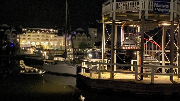 A docked boat at night with a building in the background. - Vacation home "Leuchtturmblick" in the harbor village Rheinsberg (Rheinsberg)