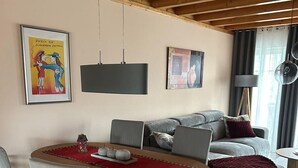 A modern living room with a dining table, grey upholstered sofa, and a red throw blanket. - Vacation home "Leuchtturmblick" in the harbor village Rheinsberg (Rheinsberg)