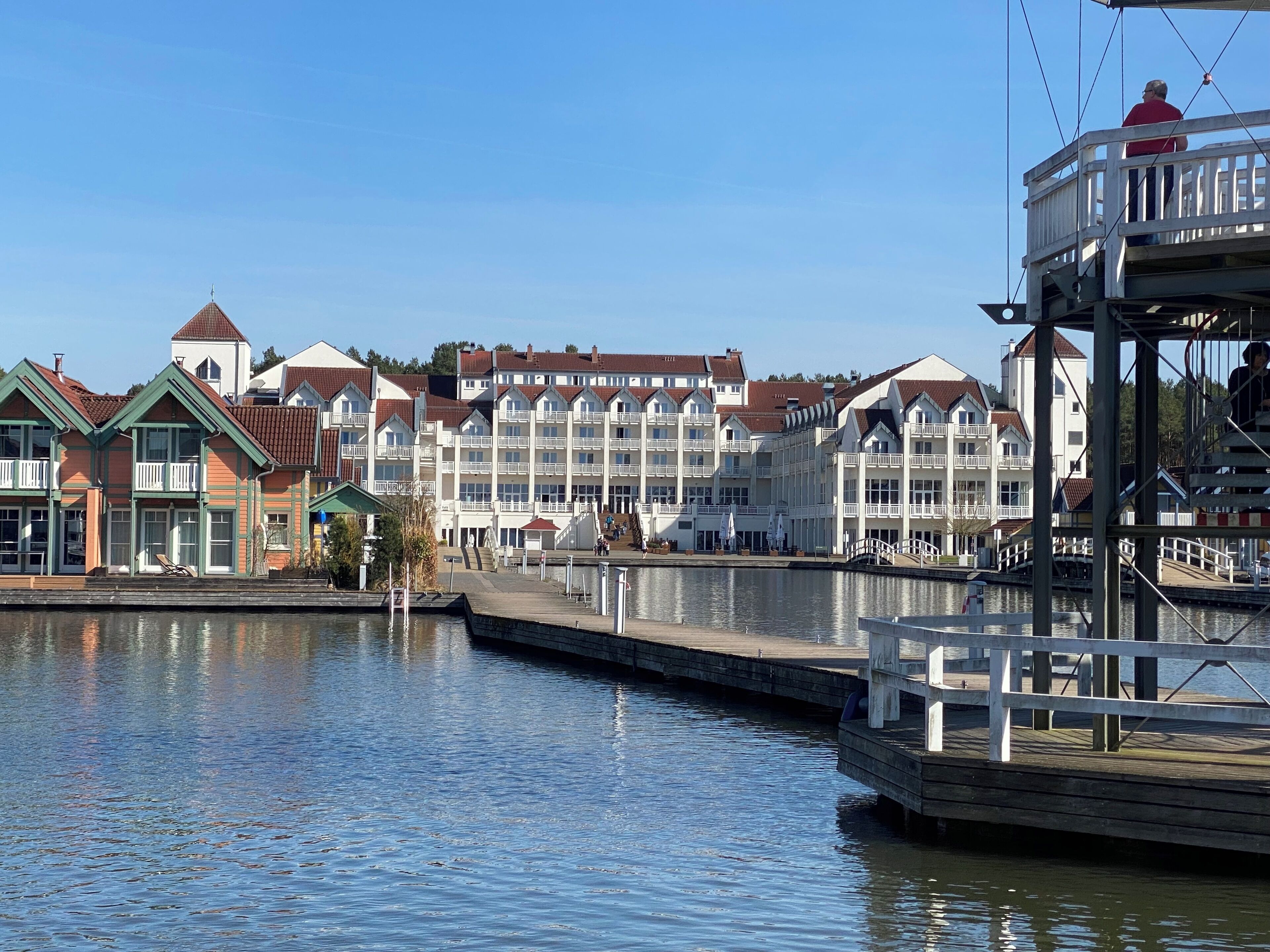 Un hôtel situé au bord de l’eau, composé de plusieurs bâtiments, doté d’un quai et d’une tour de surveillance pour les sauveteurs.