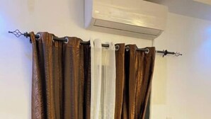 Ein braunes Ledersofa in einem Zimmer mit weißer Wand und einer Klimaanlage darüber.