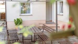 Eine Terrassenausstattung mit Holztisch und -bänken, einem Blumentopf und einem Hauseingang.
