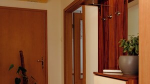 Ein Korridor mit Holzboden, einem Blumentopf, einer Holztür und einem Schrank mit Schubladen.
