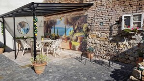 An outdoor patio with a table and chairs, a mural on the wall, and potted plants.