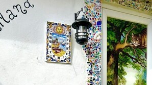 A wall with a sun decoration, a framed coat of arms, a mosaic border, and a window with a painting of a tree and a girl. - Wonderland21 (Saint-Germain-sur-Morin)