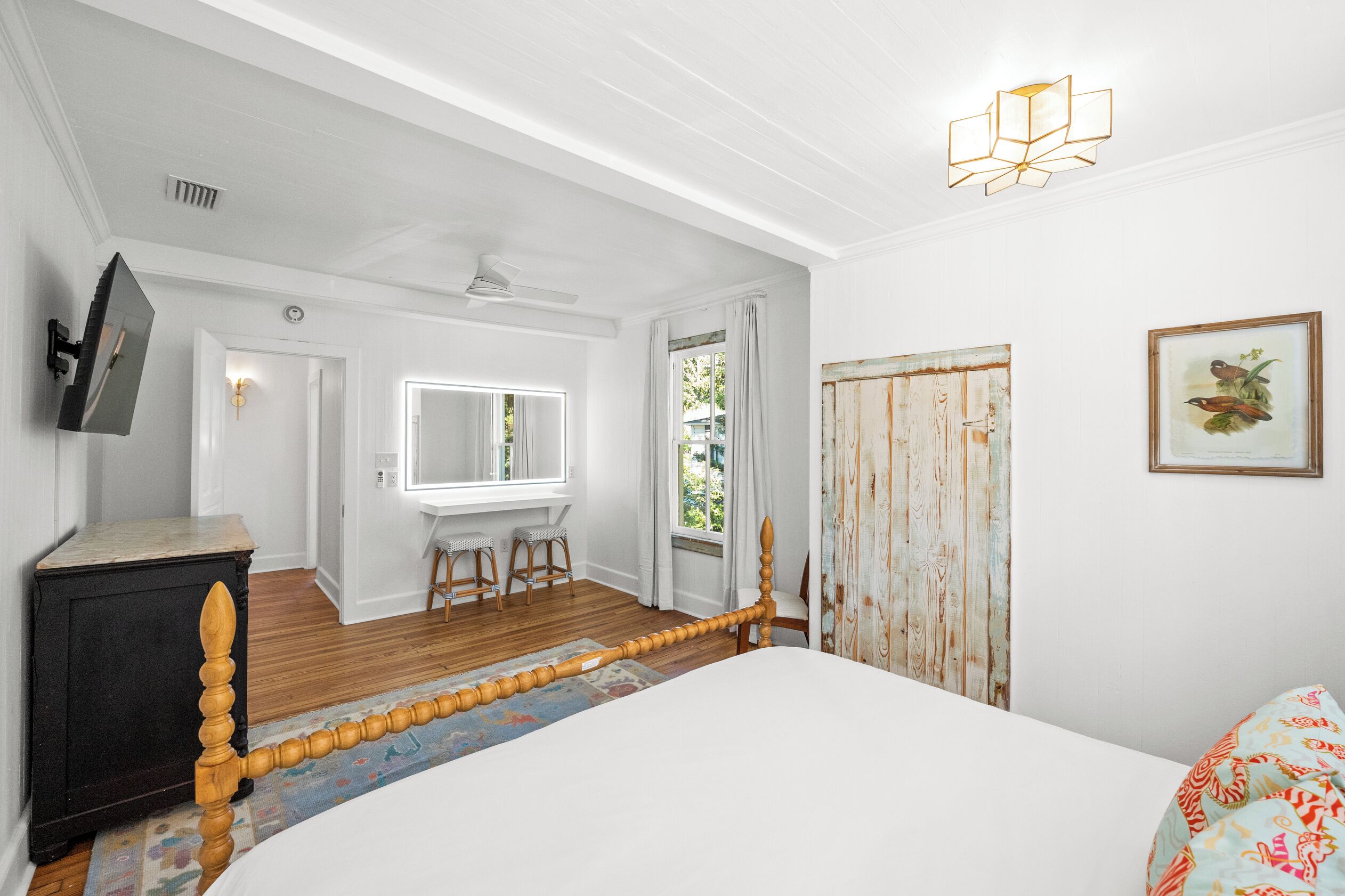 A bedroom with a bed, a dresser, a mirror, a window, and a door.